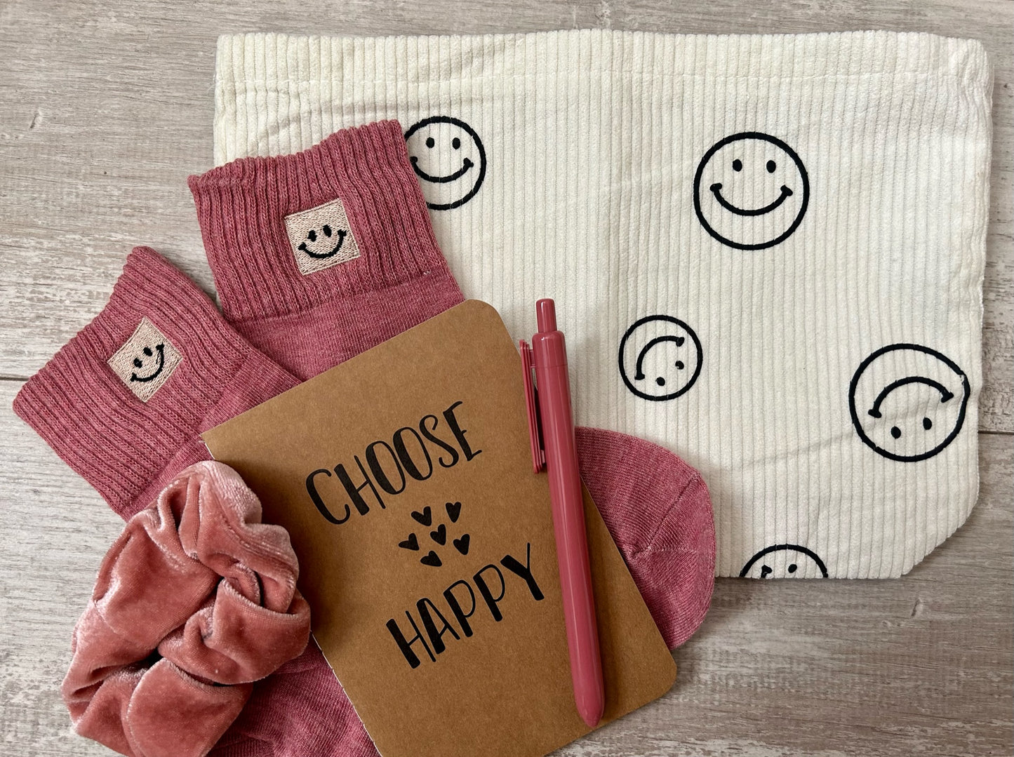 A happy gift set to brighten anyone's day. Includes a smiley face bag, a happiness journal, a pen, a scrunchie, and happy socks.