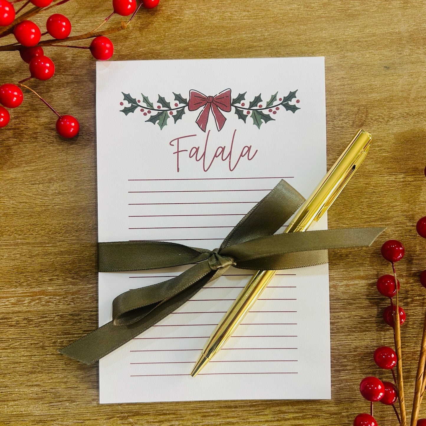 Christmas notepad and gold pen pop-by gift displayed with holiday greenery
