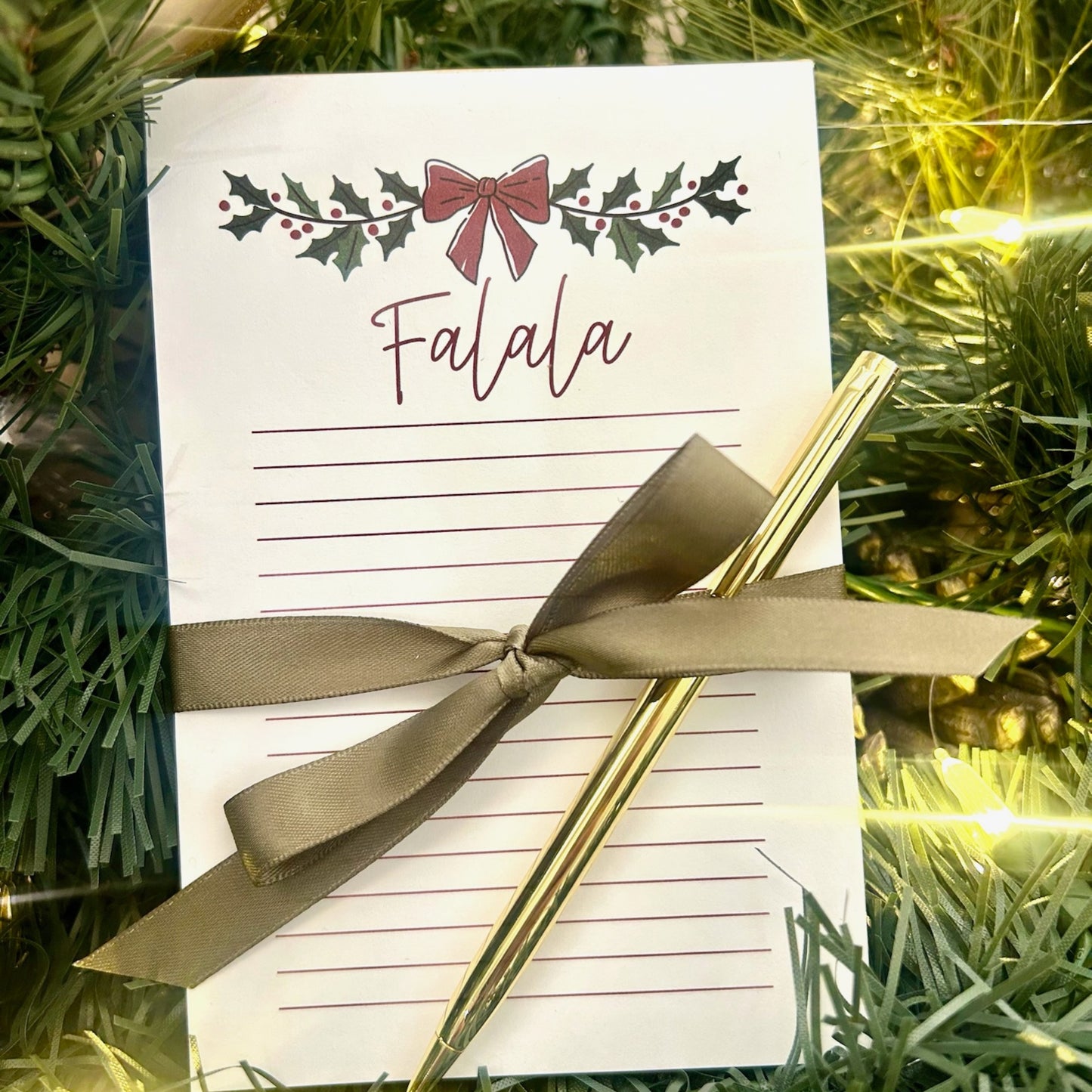 Christmas notepad and gold pen pop-by gift displayed with holiday greenery