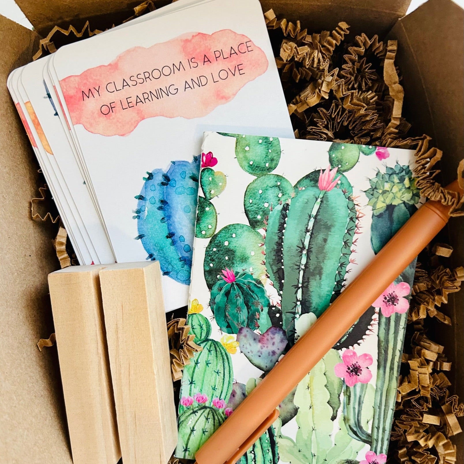 Notebook with cactus design, pencil, affirmation cards and wooden stand in a box